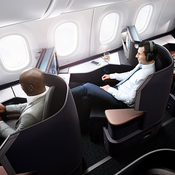 Aerial view of two guests relaxing in spacious business cabin pods on 787 Dreamliner aircraft