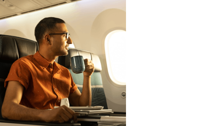 Un passager buvant dans une grande tasse à bord d’un 787 Dreamliner