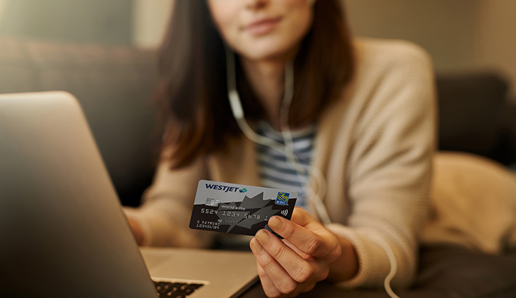 Woman holding credit card while using laptop