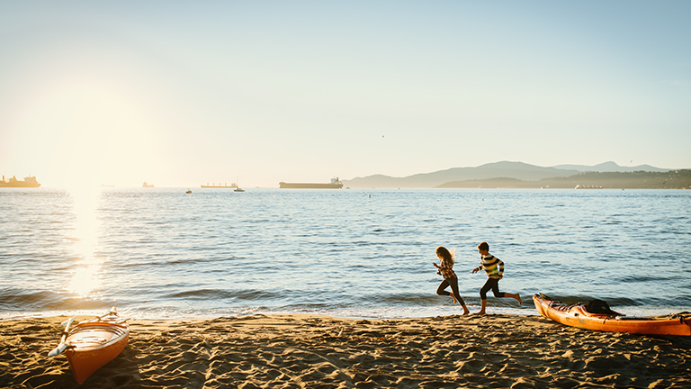 Des enfants courent sur la plage alors que des vaguelettes lèchent le rivage