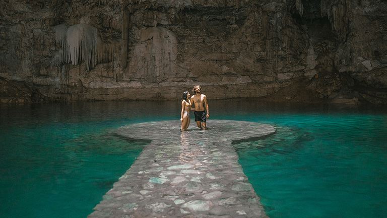 A couple standing in a cenote in Mexico. 