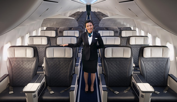 Auxiliar de vuelo de WestJet en el pasillo de una cabina Premium con asientos 2x2