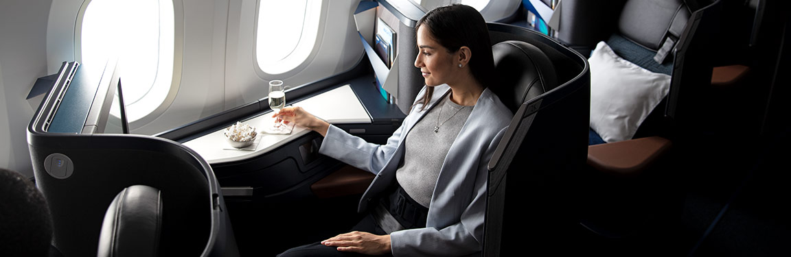Mujer disfrutando de una copa de vino espumante en un asiento Business 