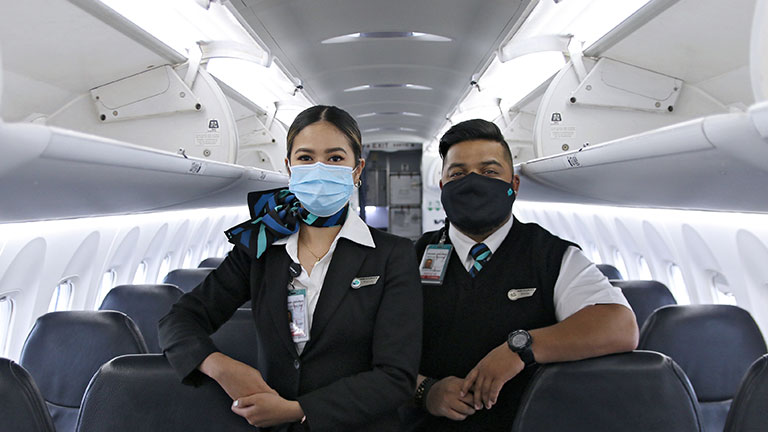 WestJet cabin crew wearing masks on board a plane