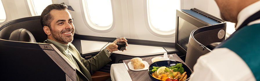 A guest in Business being served food by a WestJetter