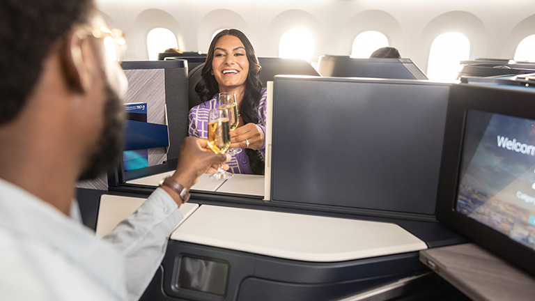 Two guests in Business Class airplane having a drink