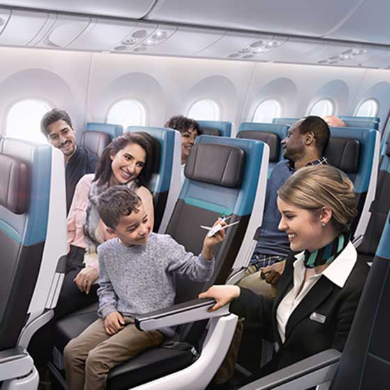 WestJet flight attendent in aisle positively interacting with seated child pretending to fly toy plane in Economy cabin
