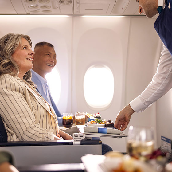 Un employé de WestJet servant une boisson à un invité dans un avion