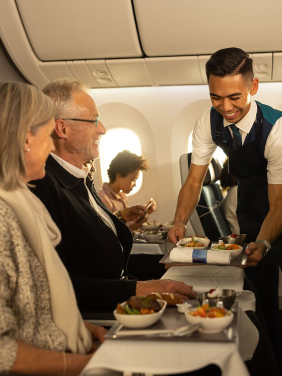 Man serving food to people on an airplane