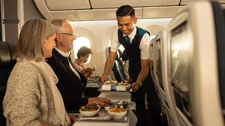 Man serving food to people on an airplane