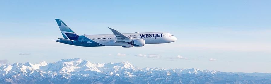WestJet aircraft flying over mountains