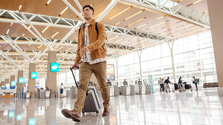 Man walking along the airport with luggage