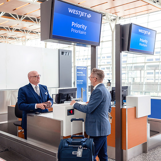 WestJetter greeting guest at Priority check-in counter.