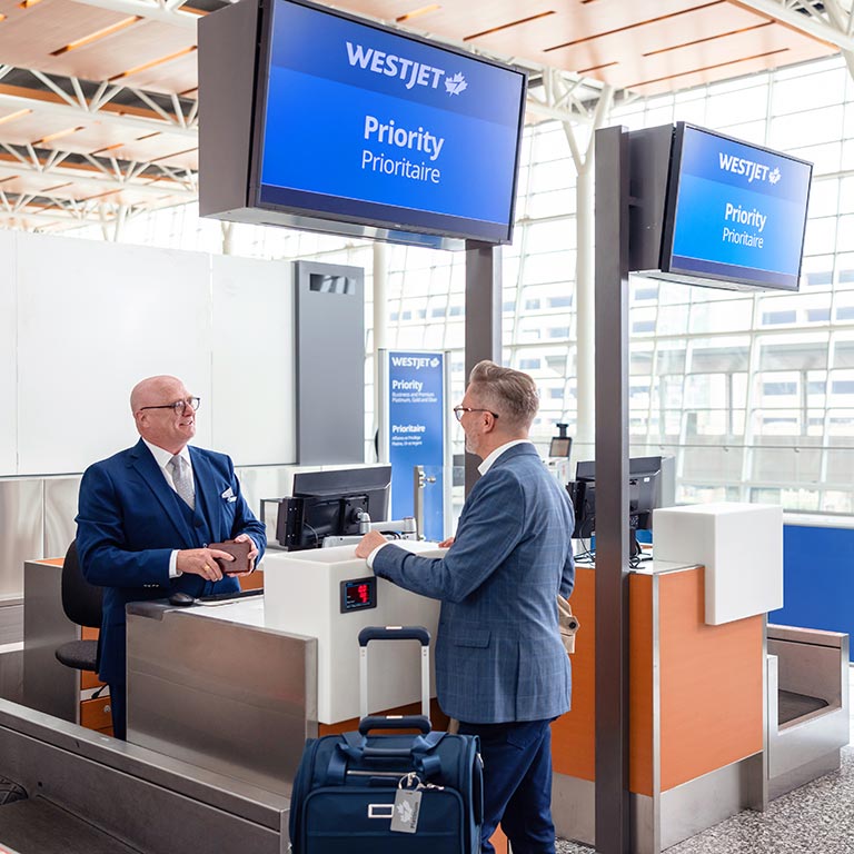 WestJetter greeting guest at Priority check-in counter.