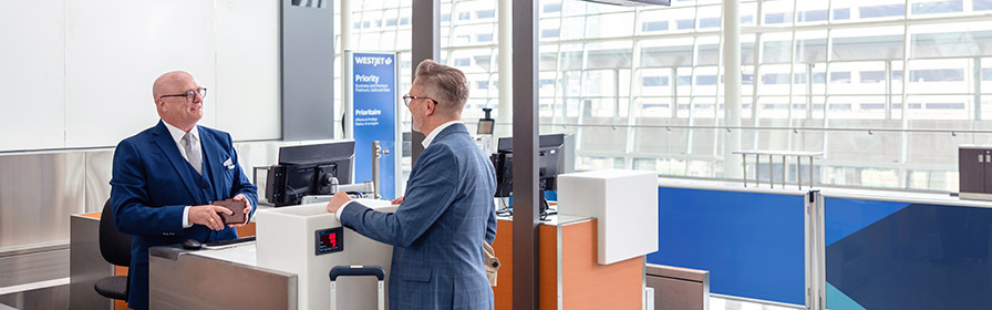 WestJetter greeting guest at Priority check-in counter.