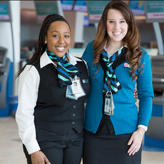 A couple of WestJet Customer Service Agents posing in an airport terminal