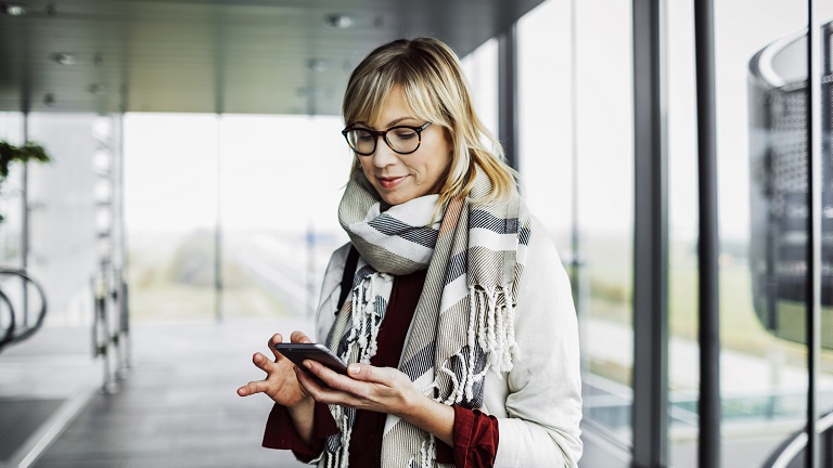 Businesswoman with smart phone standing at the airport and reading her messages