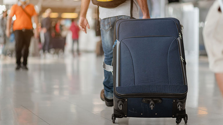 Homme tirant sa valise à travers l'aéroport