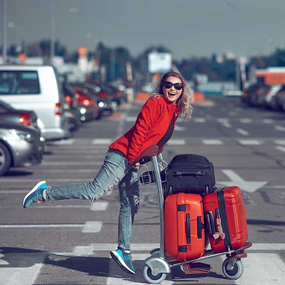Femme poussant des bagages dans le parking de l'aéroport