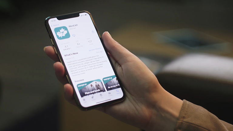 Guest holding smartphone with WestJet app