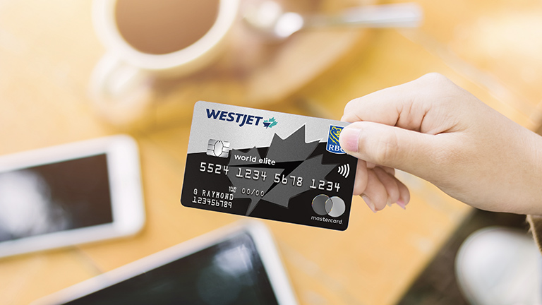 Guest holding WestJet RBC® World Elite Mastercard‡ in hand. 