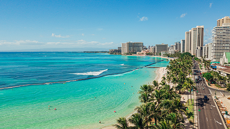Ocean waters, palm trees and buildings along Waikiki Beach, Hawaii 