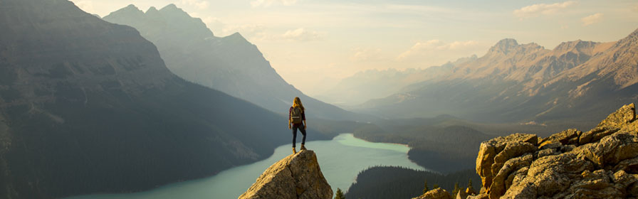 hiker on mountain overlooking pristine lake