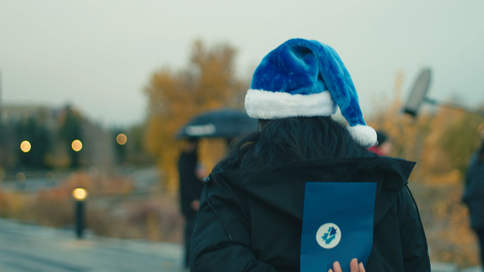 WestJetter with Blue Santa hat hiding an envelop 