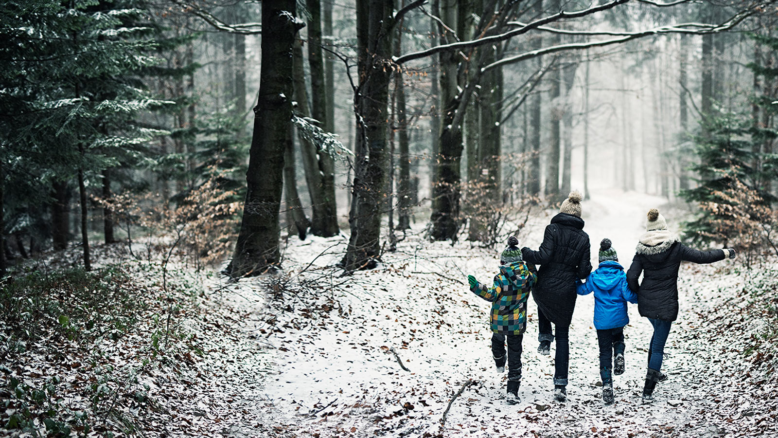 Une famille heureuse court dans une forêt hivernale