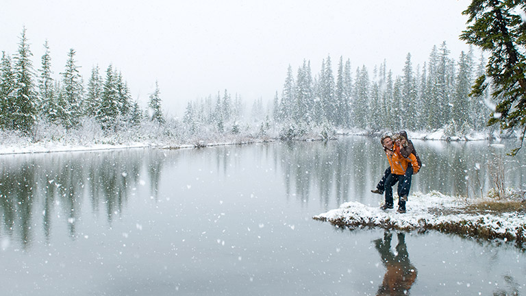 Couple walking along a snowy lake