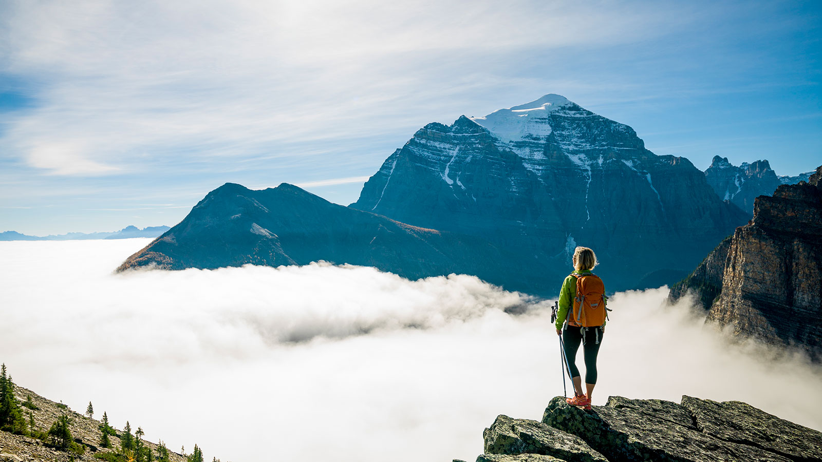 Une randonneuse se tient au sommet d'une montagne en Alberta
