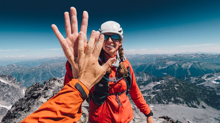 Hiker high-fiving on top of a mountain