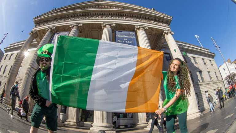 Two people holding up an Irish flag