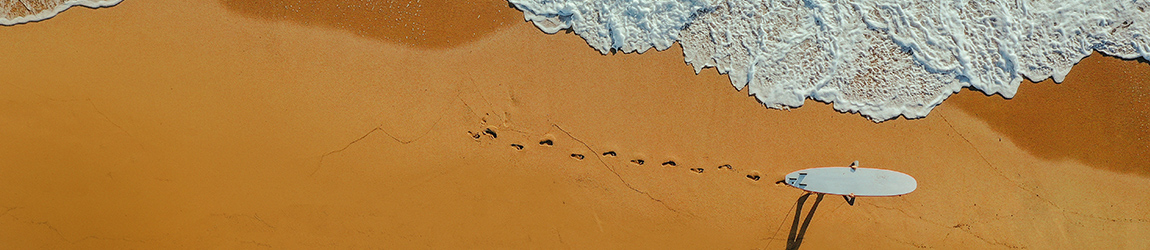 Surfer marchant sur une plage de sable