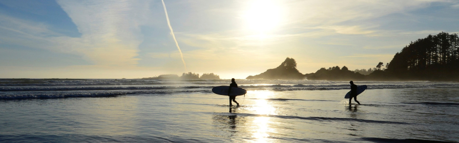 Deux surfeurs sur une plage alors que le soleil se couche