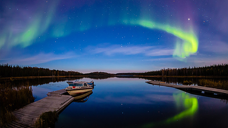 Intense Northern Lights (Aurora borealis) and their reflection across a lake.