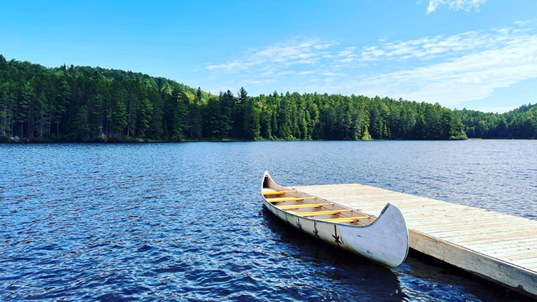 Scenic view of canoe on lake against a blue sky