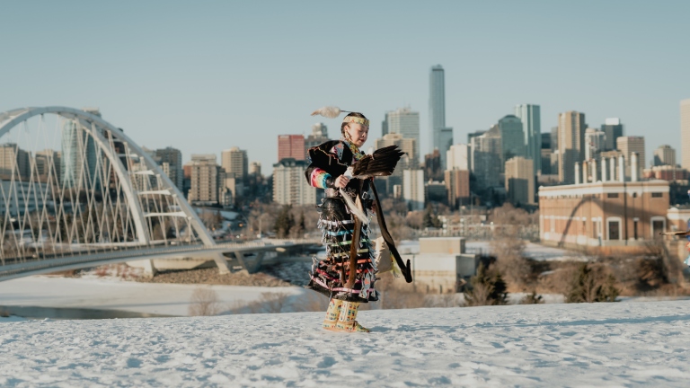 Jingle dress dancer in front of Edmonton skyline