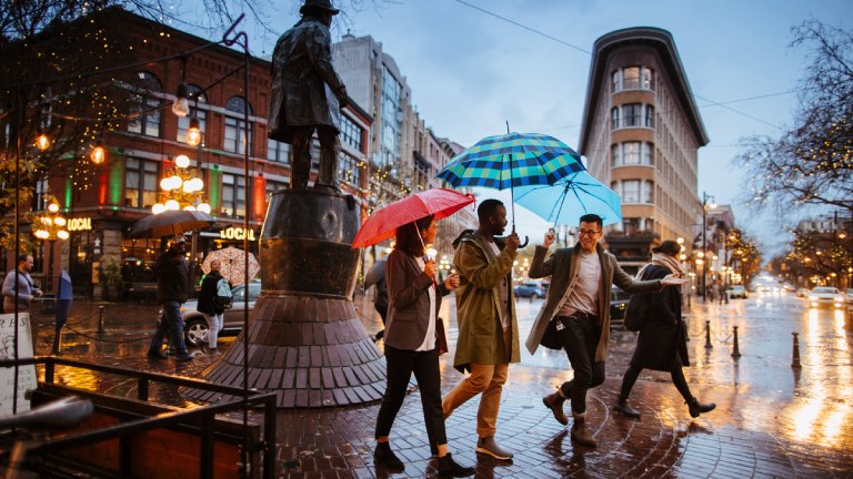 Friends walking with umbrellas in Gas Town Vancouver