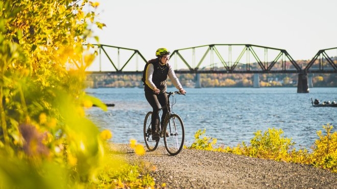 Woman riding bike along river path
