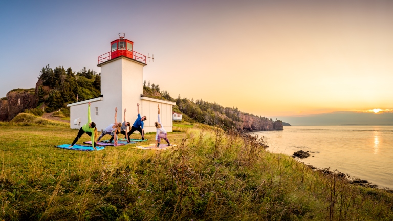 Group doing yoga in front of lighthouse