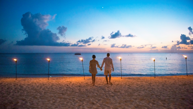 Un couple marchant sur la Seven Mile Beach au coucher du soleil