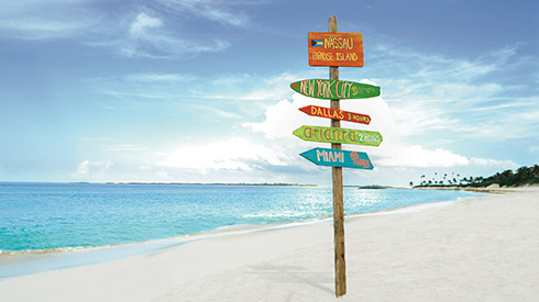 Sign in the white sand in Nassau showing the distance to nearby cities