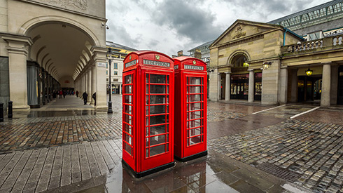 Two red telephone booths side by side on a rainy day