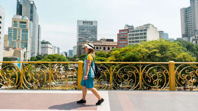 Woman walking along Viaduto do Cha with the city in the background.