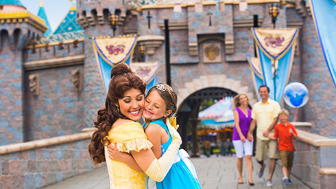 Belle with a guest smiling outside the Sleeping Beauty Castle