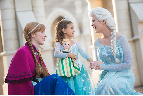 Disney characters Anna and Elsa in princess dresses with a guest