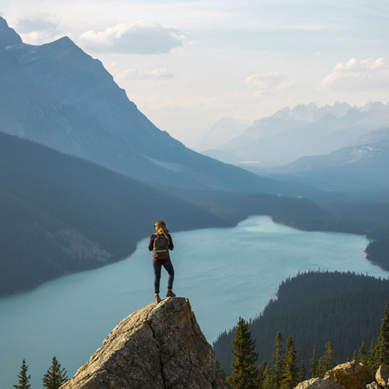 Une femme au sommet d'une montagne, devant un lac