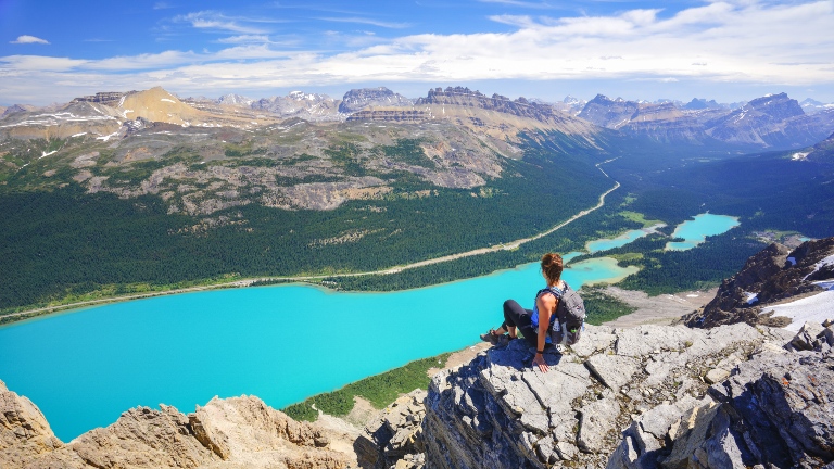 Person sitting on top of a mountain overlooking a lake