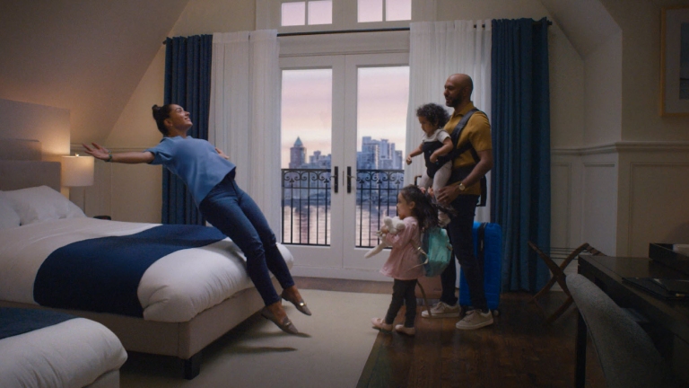 Woman jumping backwards onto hotel bed